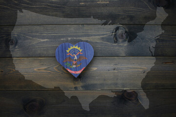 wooden heart with national flag of north dakota state near united states of america map on the...