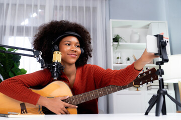 Host channel of beautiful African woman influencer setting smartphone, sing with play guitar in...