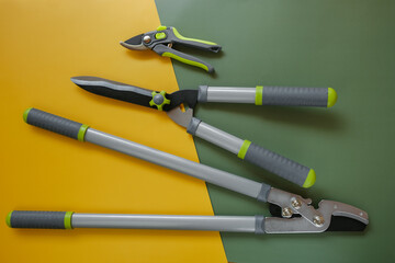 Secateurs, loppers and hedge trimmers on a yellow-green background.Garden tool set and equipment ....