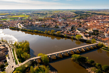 Scenic drone view of ancient Spanish city of Zamora on banks of Duero river overlooking medieval stone bridge on sunny spring day.. - obrazy, fototapety, plakaty