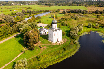 Drone view of the ancient white-stone Church of the Intercession on the Nerl on a summer day,...