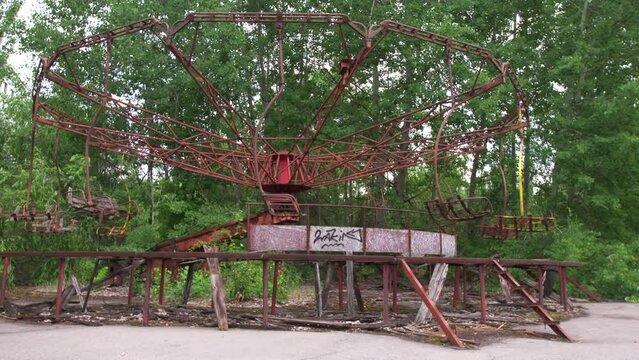 Abandoned carousel in the city of Pripyat. The whole playground was overgrown with greenery and trees. Consequences of the Chernobyl disaster.