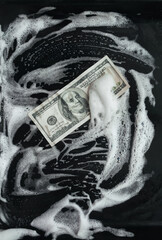 100 dollar bill lies in foam on a baking sheet. View from above. Concept of money laundering, criminal and shadow business.