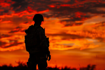 Minimalistic shot of a soldier's silhouette against a fiery sunset.  - obrazy, fototapety, plakaty