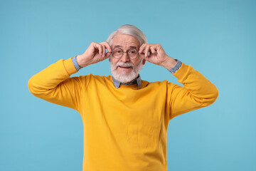 Naklejka premium Portrait of stylish grandpa with glasses on light blue background
