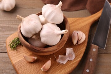 Fresh garlic and knife on wooden table, closeup. Above view