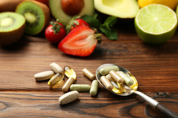Different vitamin pills and fresh fruits on wooden table