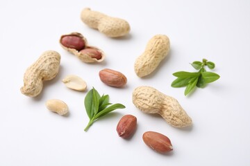 Fresh peanuts and leaves on white table, closeup