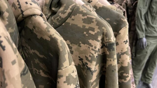 Assorted military hoodies in camouflage patterns displayed on racks within a store