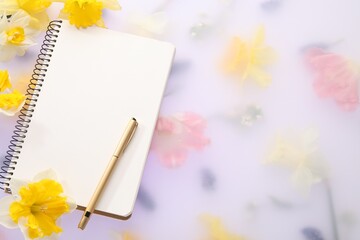 Guest list. Notebook, pen and daffodils on spring floral background, flat lay. Space for text