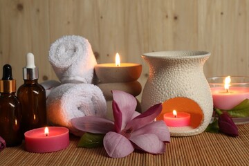 Aromatherapy. Scented candles, bottles, flower and towels on bamboo mat