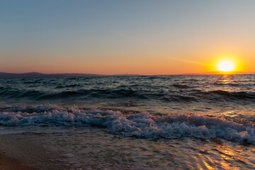 Naklejka premium Sea waves on the golden sand at beach. Beautiful tropical nature beach sea ocean with sunset or sunrise for travel vacation