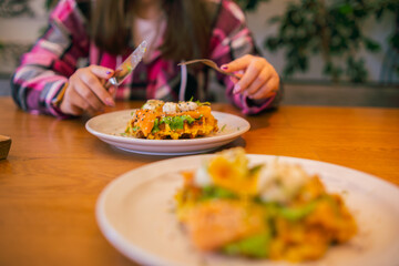 Potato waffle with salmon, poached egg in spinach sauce on white plate.