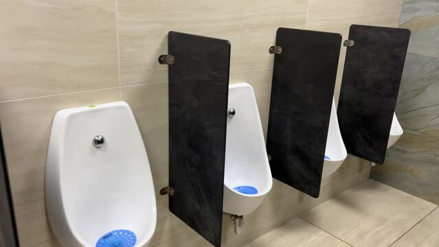 Rows of modern urinals with a sensor WC flush in a public men's room