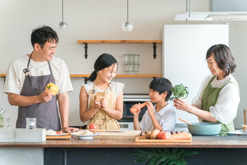 家のキッチンで子供と一緒に料理・クッキング・お手伝いする子供と夫婦・親子・家族
