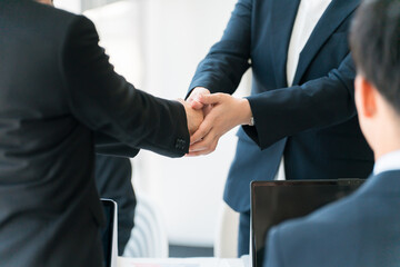 企業のオフィス・会議室で握手をして契約を結ぶビジネスウーマンの手元
