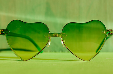 Sunglasses with green glasses in the shape of hearts. Fashion accessories for summer vacation....