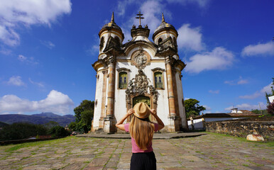 Tourism in Ouro Preto, Brazil. Back view of young tourist woman in Ouro Preto visiting Saint Francis of Assisi church in Minas Gerais state, Brazil. UNESCO world heritage