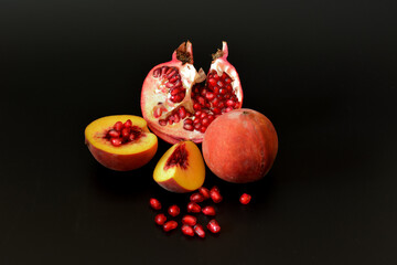Peach with pomegranate, ripe fruits on a black background.
