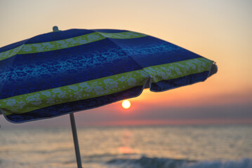 Striped beach umbrella on the beach. Beach umbrella on a sunny day, sea in background. Blue...