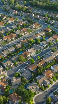 Vertical video. Suburban housing district area in USA. American homes in quiet neighborhood at golden hour. Beautiful green suburb aerial at scenic sunset. Aerial drone shot of residential Los Angeles
