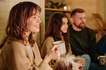 Happy Caucasian woman holding mug enjoying spending winter evening with her husband and daughter at home, copy space
