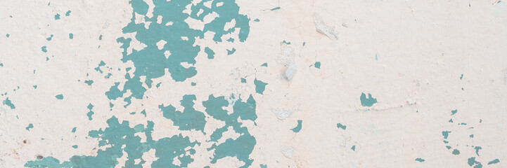 Peeling paint on the wall. Old concrete wall with cracked flaking paint. Weathered rough painted surface with patterns of cracks and peeling. High resolution texture for background and design. Closeup