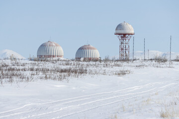Aeronautical radar in the snowy tundra. Huge locators support aircraft flights. Large domes (radiotransparent shelters) of a radar station. - 795971177