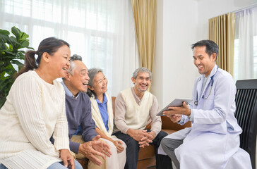 A positive emotion mature male doctor using digital tablet explaining to group of playful senior patient and they are laughing, concept for health care and medical,elderly care,group consultation