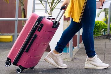 Happy Latina woman with her pink suitcase going on vacation. Excited woman ready to travel and...