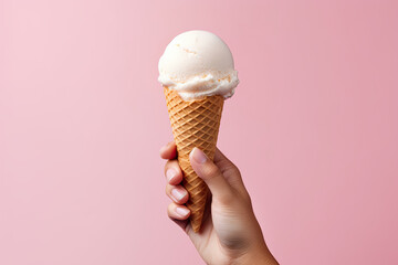 Female hand holding ice cream cone with white scoop on pink background