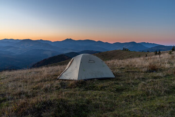 Tourist tent in the mountains. Sunrise in the mountains. Tourist camp and sunrise. Outdoors.
