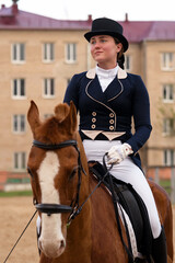 Dressage rider on chestnut horse with urban backdrop