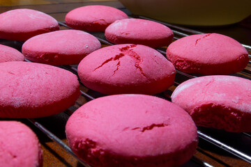 many simple pink cookies a little dusted with flour and cracked, placed on a metal rack made in a homemade way