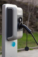 Vertical street photo. Close up of gray electric car charging station in Tbilisi. Plug is plugged...