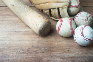 Close up old baseball and wooden bat on a wooden table. select focus.
