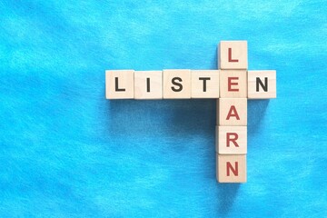 Listen and learn concept. Crossword puzzle flat lay in blue background.