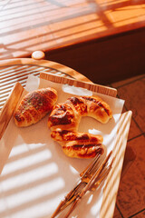 Golden fresh buns on a round table in the sunlight. Delicious pastries in the morning for breakfast.