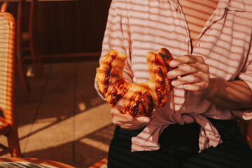 A woman in a pink shirt holds a fresh bun. Fresh pastries in the morning for breakfast