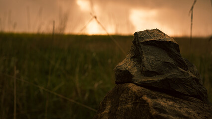 Close-up of a stone in a meadow at sunset.