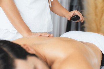 Hot stone massage at spa salon in luxury resort with day light serenity ambient, blissful man...