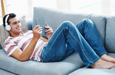 Smile, headphones and man with tablet on sofa for online streaming, video and watching movie....