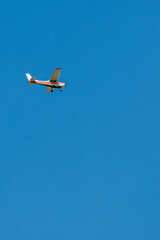 A sports plane flies in the blue sky on a spring day