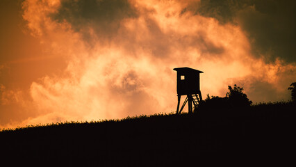 Silhouette of lifeguard tower on hill with sunset sky background