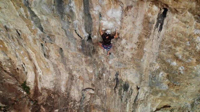 Aerial drone view of strong female climber climbing a difficult sport climb route in a steep wall at Kalymnos island, Greece. High quality 4k footage.