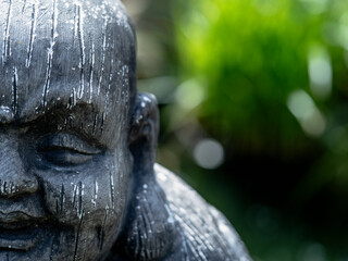 Statue of a Buddhist monk in a garden, close-up - obrazy, fototapety, plakaty