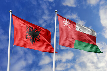 3d illustration. Albania and Oman Flag waving in sky. High detailed waving flag. 3D render. Waving in sky. Flags fluttered in the cloudy sky.