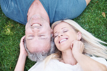Mature, happy couple and outdoor relax on grass from above for marriage anniversary, travel or relationship. Man, woman and top view in garden park in New Zealand for holiday trip, peace or nature