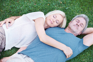 Man, woman and mature or relax on grass for afternoon nap in nature backyard for resting, weekend or sleeping. Couple, embrace and bonding connection with peaceful calm in Australia, meadow or spring