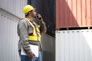 Middle east logistic worker foreman use walkie talkie and notebook computer working at container site	